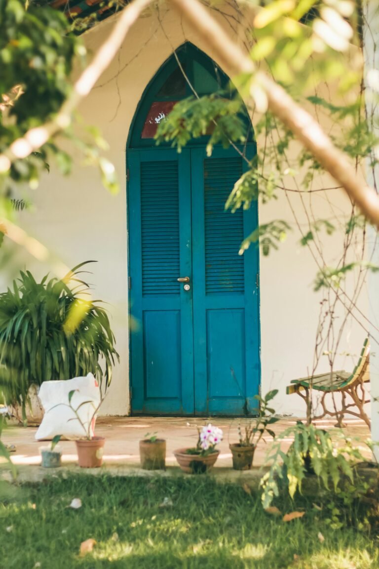 Rustic blue door surrounded by green plants and a garden path.