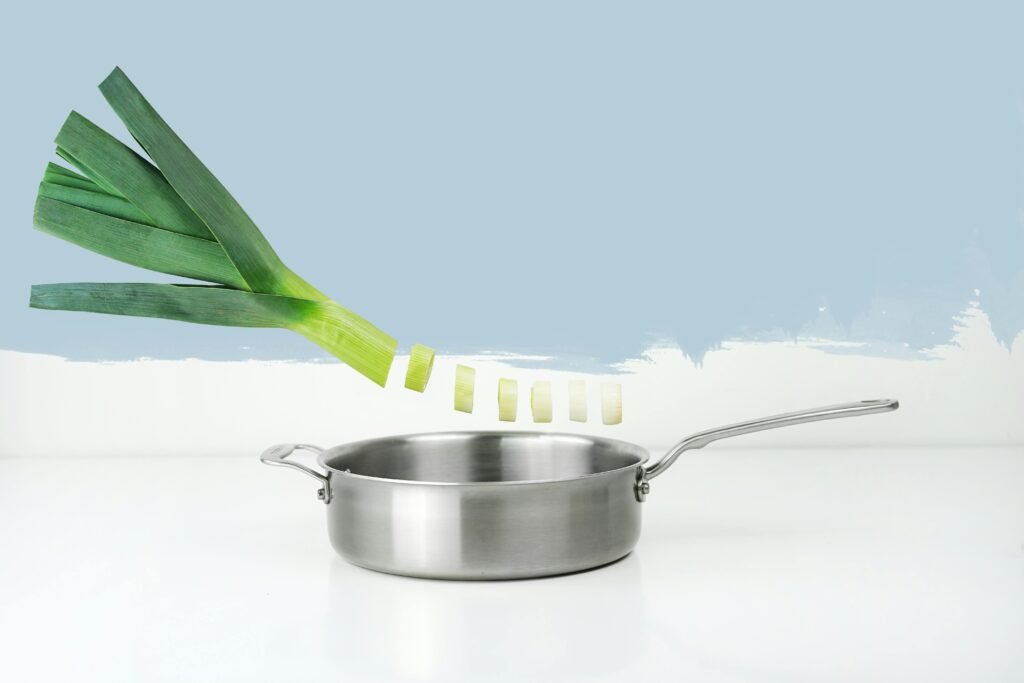 Artistic image with leek and stainless steel pan in minimalist style.