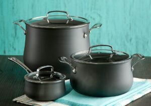 Stylish black pots and saucepan on a turquoise backdrop, perfect for kitchen decor.