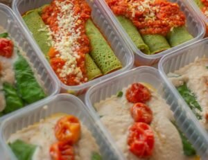 An assortment of healthy, colorful meal prep boxes featuring vegetables, grains, and proteins.