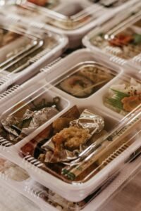 Close-up of assorted bento boxes with sushi and rice in disposable packaging.