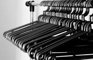 A modern grayscale image of clothes hangers neatly arranged on a metal rack indoors.
