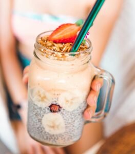Delicious and fresh summer smoothie in a mason jar, topped with strawberries and granola.